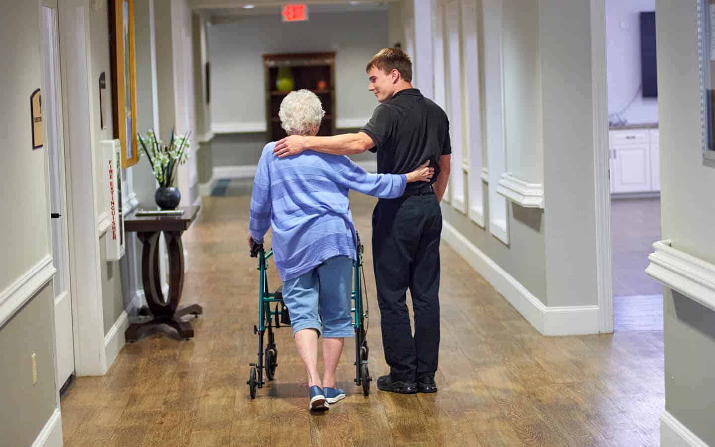 caregiver and resident walking arm in arm down the hallway