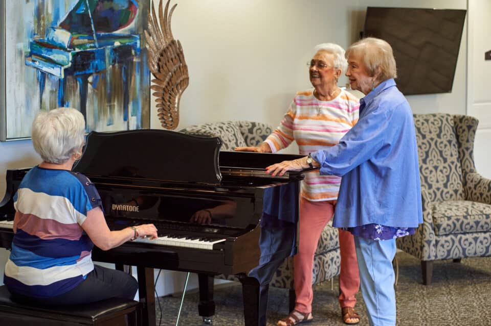 residents talking and singing around the piano