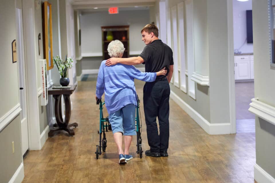 resident and caregiver walking arm in arm down the hallway